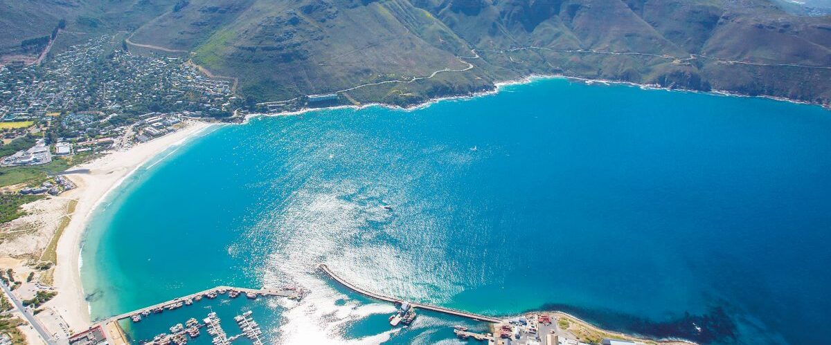 Cape Town, Western Cape, South Africa - 12.22.2020: Aerial photo of a Hout Bay Harbour with Chapmans Peak in the background