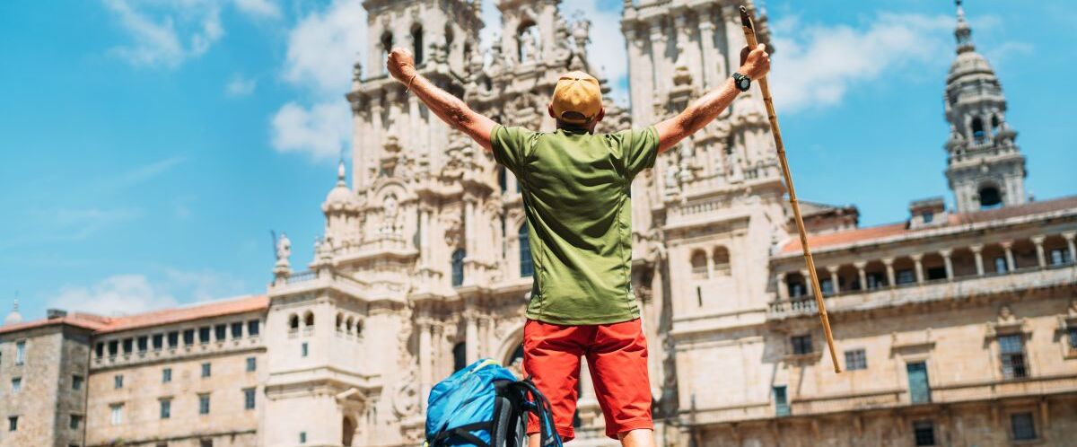 Young backpacker man pilgrim standing with raised arms on the Ob