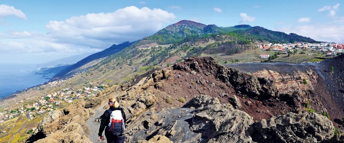 Hiker on the San Antonio volcano near Fuencaliente, town of Los Canarios at back, La Palma, Canary Islands, Spain, Europe